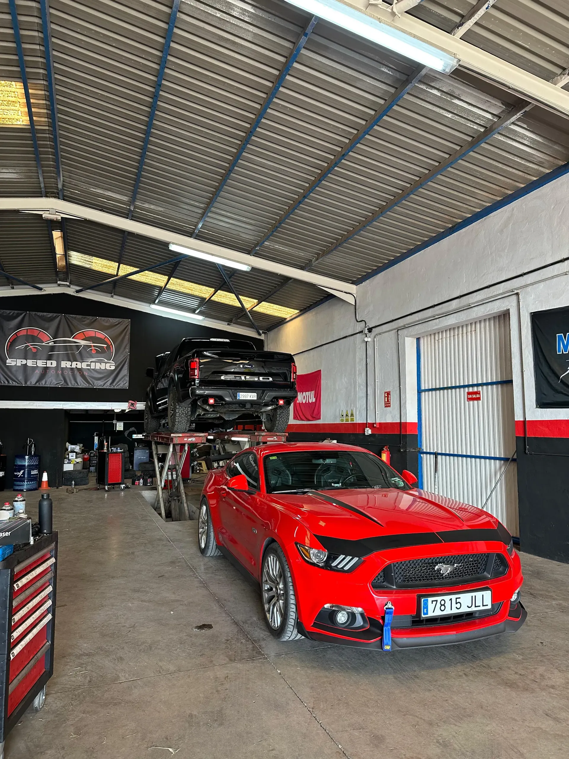Un mustang rojo está estacionado en un garaje.