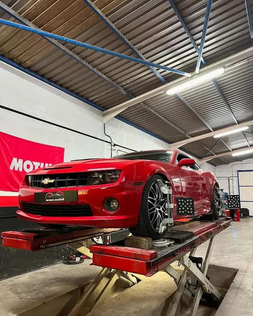 Un coche rojo está estacionado en un elevador en un garaje.