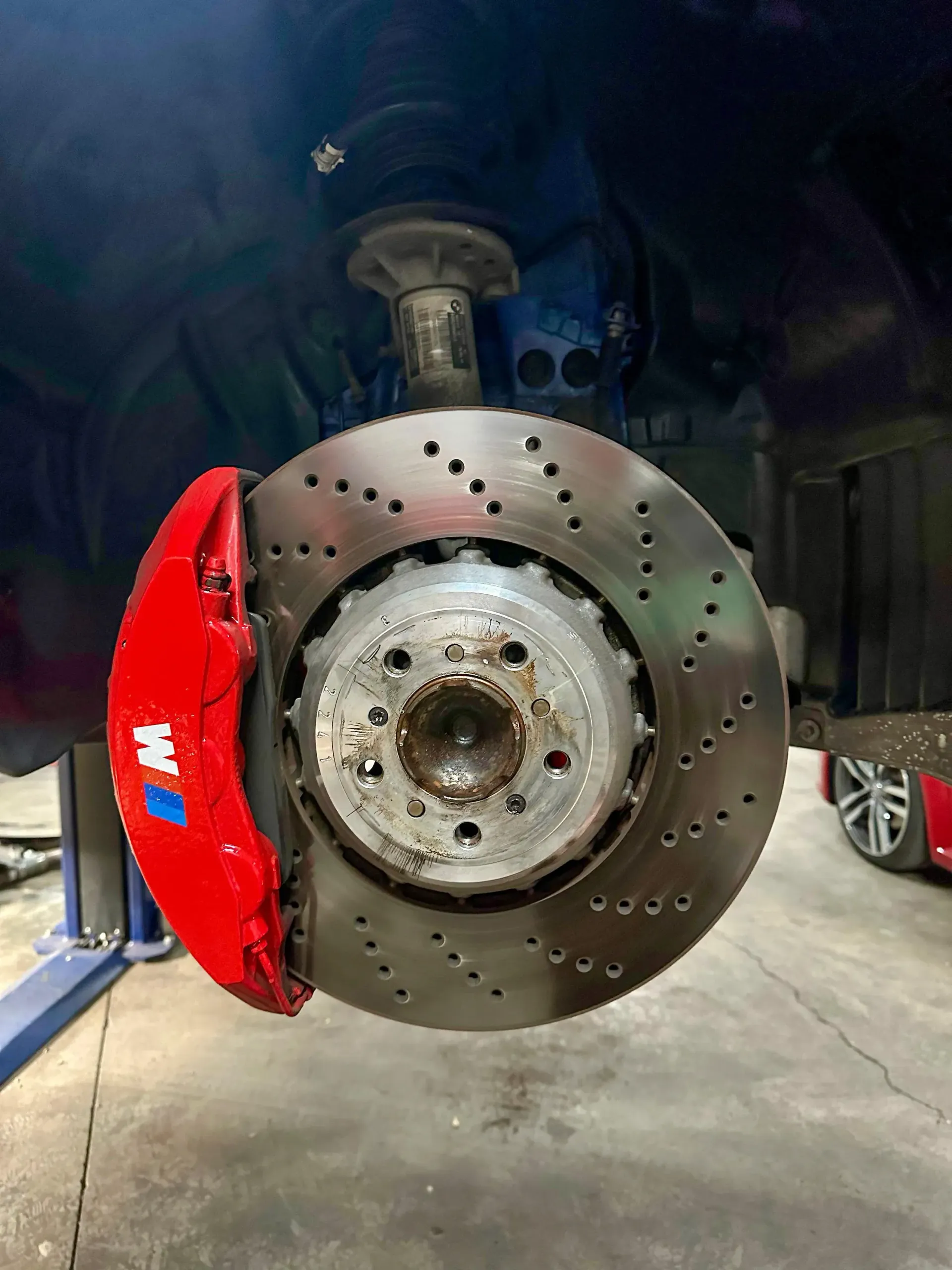 Un primer plano de un disco de freno en un automóvil con una pinza de freno roja.
