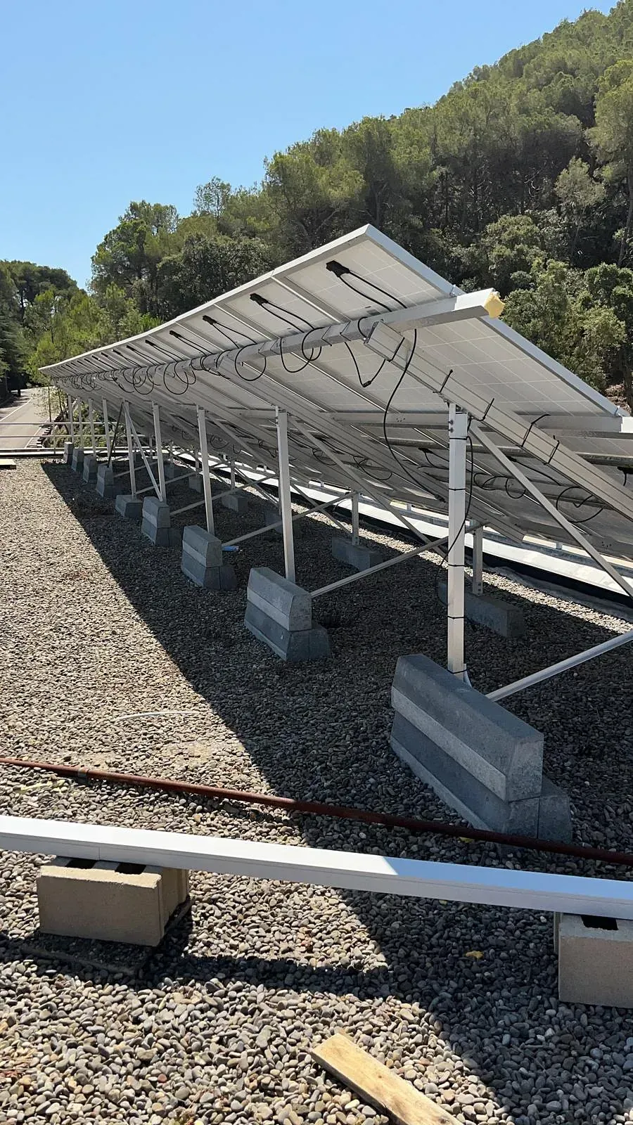 Una fila de paneles solares colocados encima de un campo de grava.