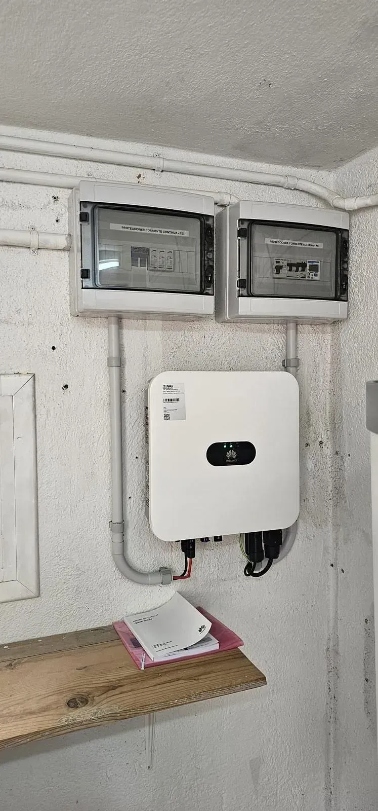 Una caja blanca está colgada en una pared al lado de un estante de madera.