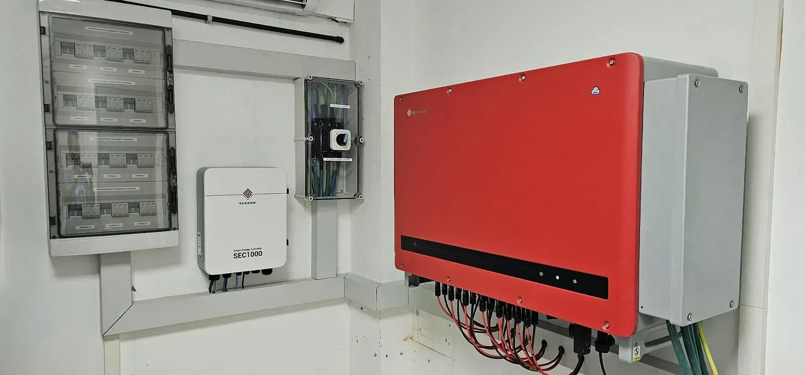 Una caja eléctrica roja está en una pared al lado de una caja blanca.