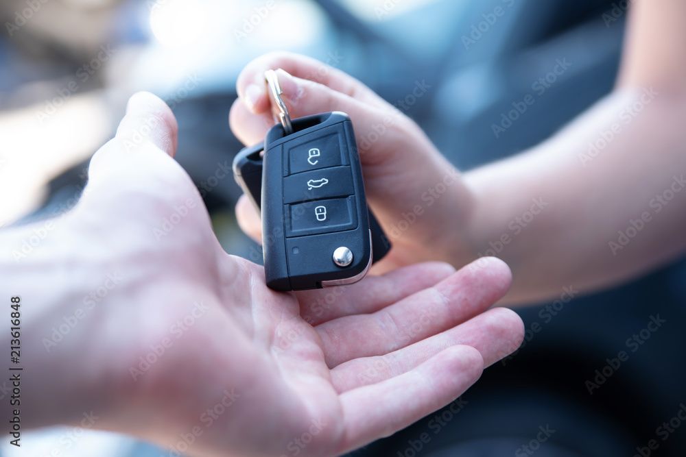 Ein Paar mit einem Verkäufer in einem Autohaus betrachtet einen roten Wagen.