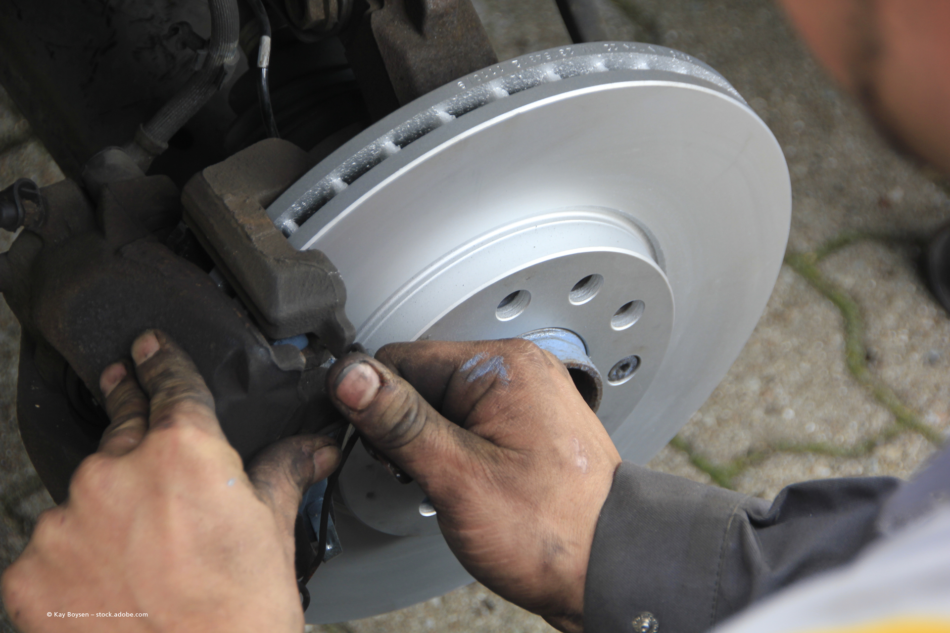 Ein Mechaniker montiert in einer Werkstatt mit schwarzen Handschuhen einen Motorradmotor.