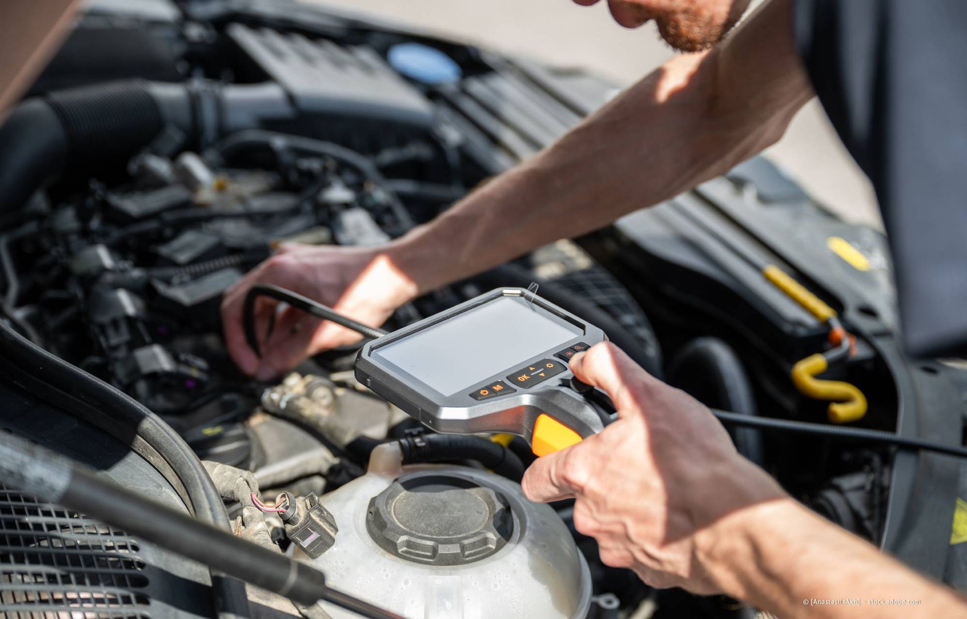 Ein Mechaniker verwendet eine Inspektionskamera zur Diagnose eines Automotors.