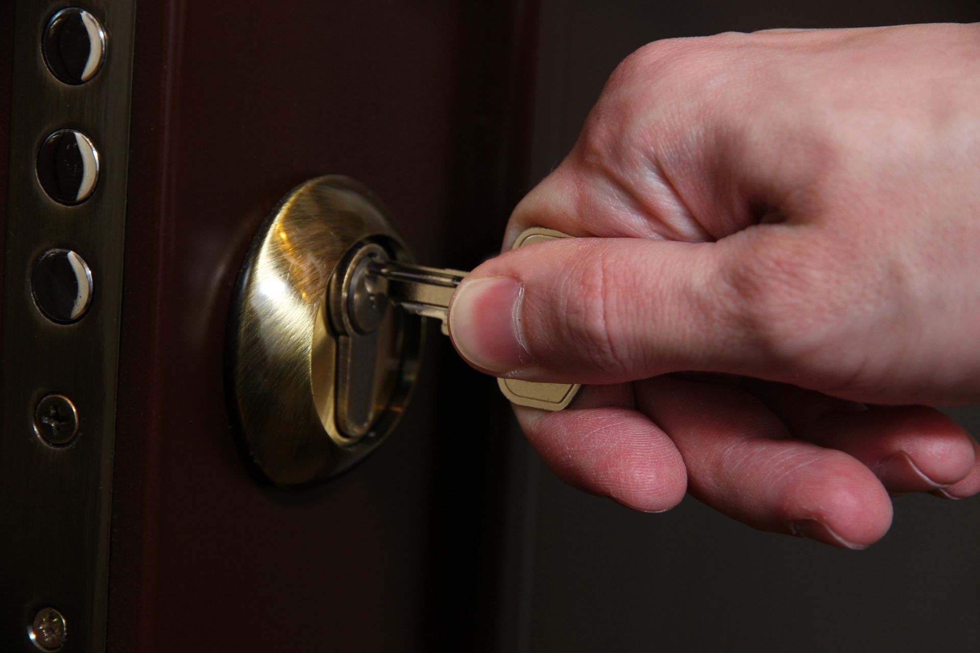 Una persona sostiene una llave en la cerradura de una puerta.