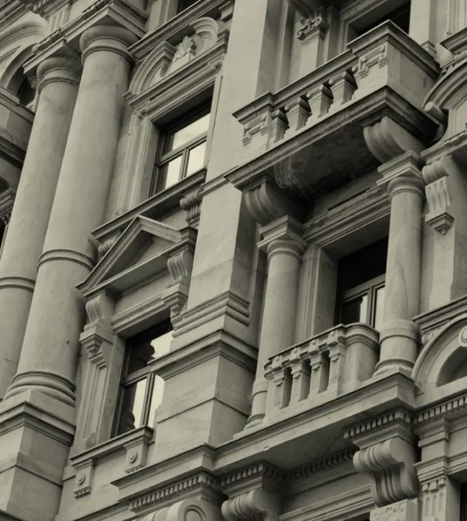 Fachada de edificio de piedra ornamentada con columnas, ventanas y balcones decorativos.