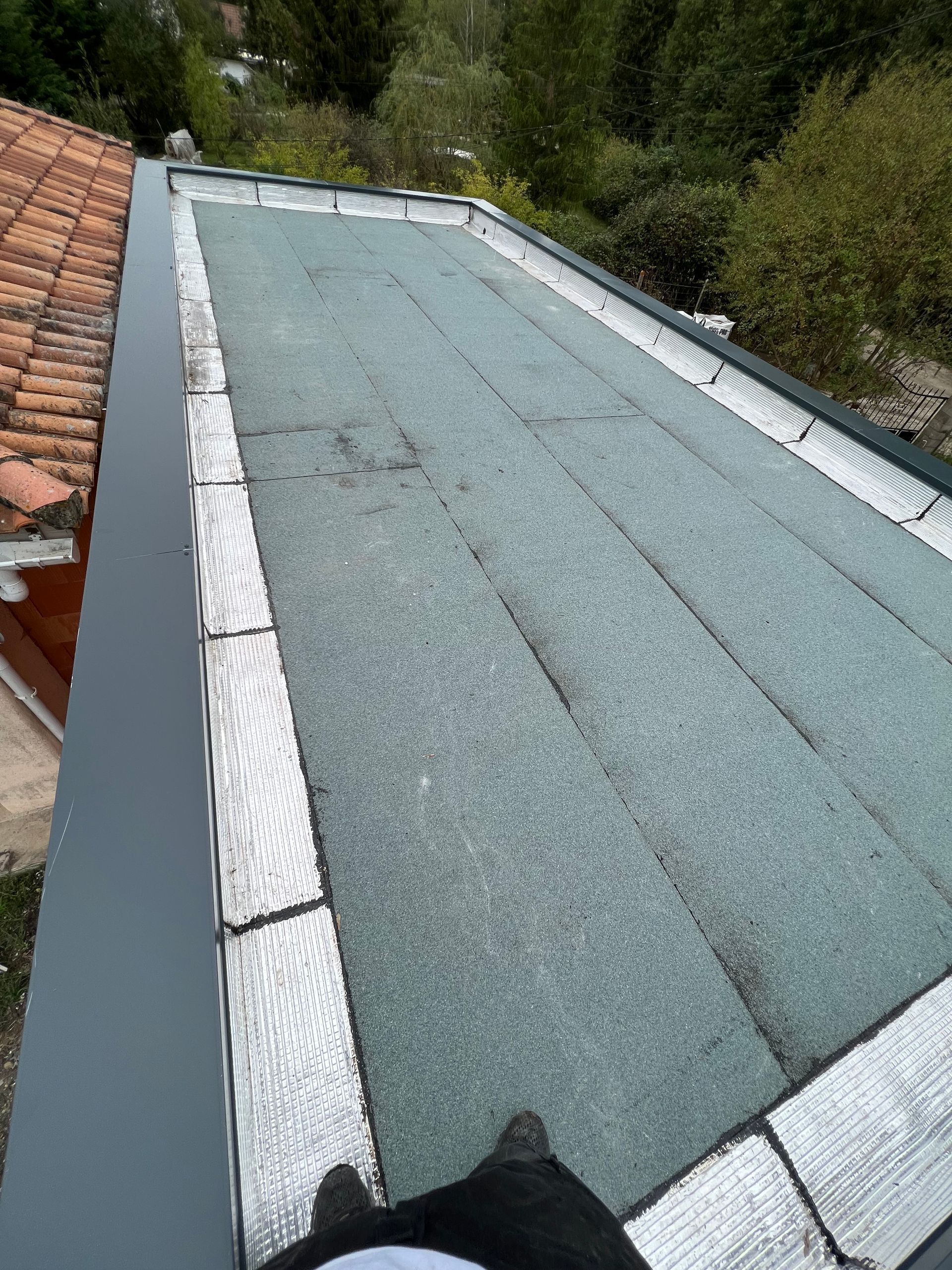 Toit plat avec bordure gris foncé et surface gris verdâtre.