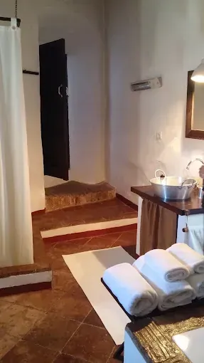 Baño con toallas blancas, puerta oscura y escaleras que conducen hacia arriba.