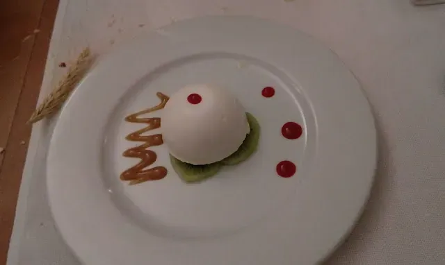 Postre blanco con puntos rojos y remolinos marrones sobre un plato blanco.
