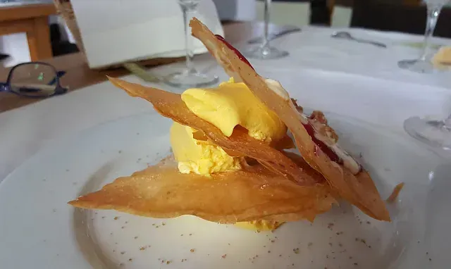 Postre amarillo con masa crujiente sobre plato blanco.