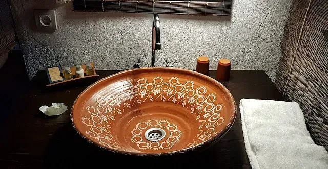 Baño rústico con lavabo y grifo estampados en color marrón y una toalla blanca doblada.