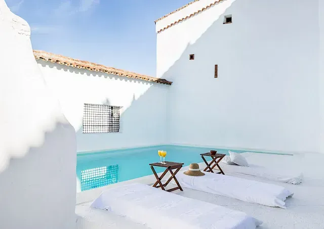 Un edificio blanco con una piscina al fondo.