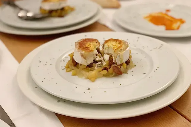 Dos medallones de queso de cabra sobre chutney de manzana, servidos en un plato blanco.
