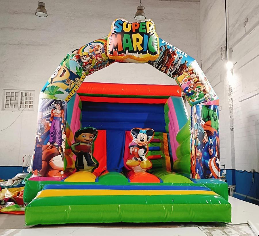 Castillo inflable con temática de Super Mario y toboganes. Presenta varios personajes de dibujos animados y colores vibrantes.