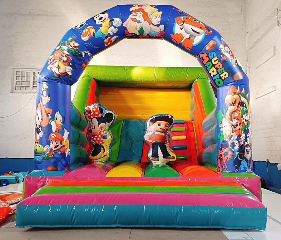 Castillo inflable colorido con personajes de Super Mario. Tiene arco, tobogán y figuras de Minnie Mouse y un niño con overol.