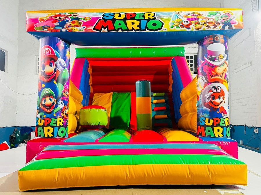 Un colorido castillo inflable con temática de Super Mario que presenta personajes como Mario y Luigi; detalles en rojo, amarillo, azul y verde.