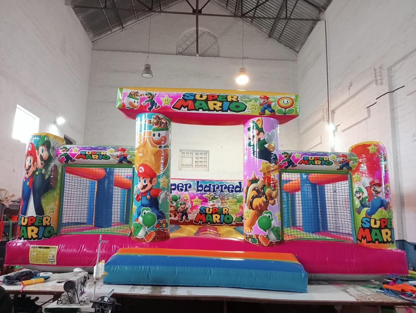 Una casa inflable con Mario y Luigi encima está en un almacén.