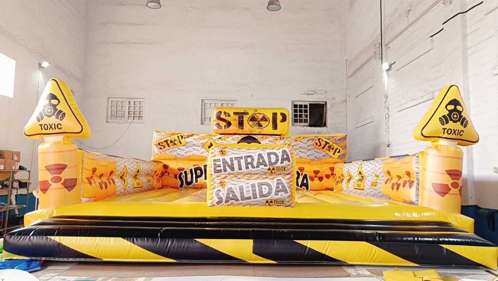 Un gran castillo inflable de color amarillo y negro con señales de advertencia.