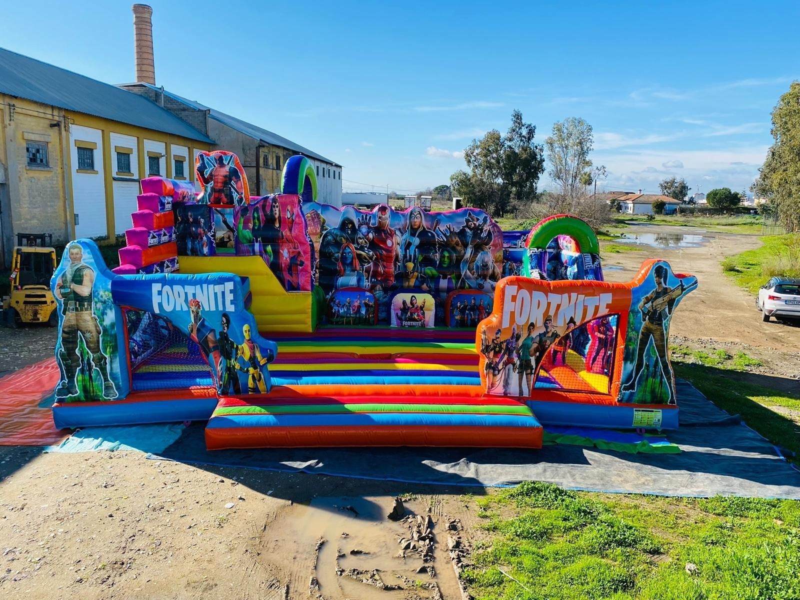 Castillo inflable con temática de Fortnite. Colorido, con toboganes, escaleras y gráficos de personajes, ubicado al aire libre en un día soleado.