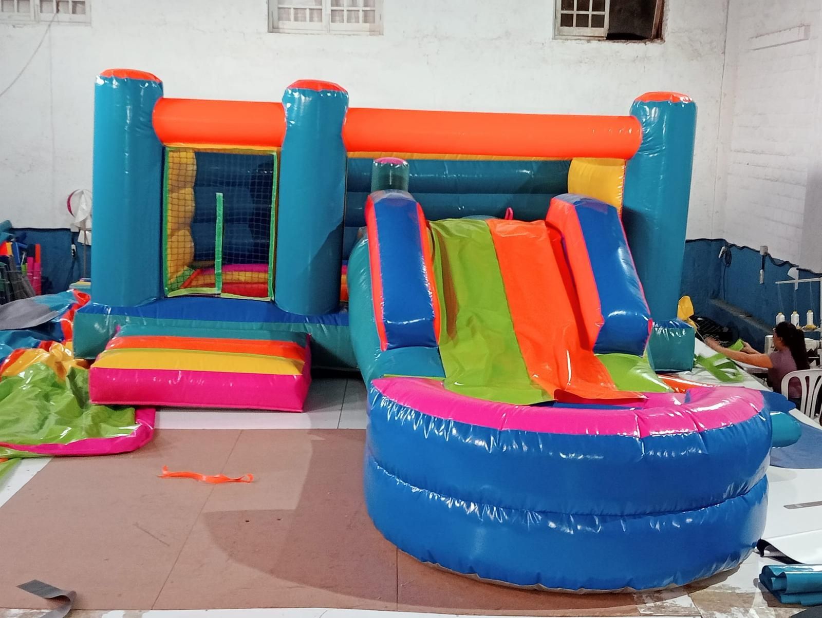 Una casa inflable colorida con un tobogán y una piscina.