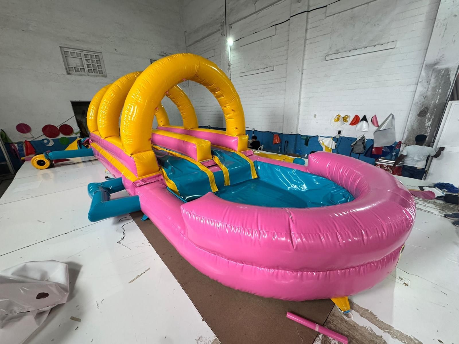 Un tobogán de agua inflable de color rosa y amarillo está en una habitación.