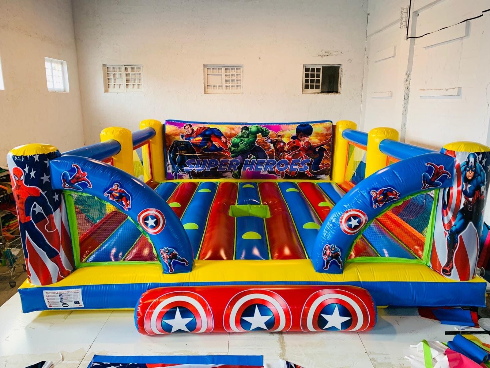 Una casa inflable grande con el Capitán América y Hulk encima está en una habitación.