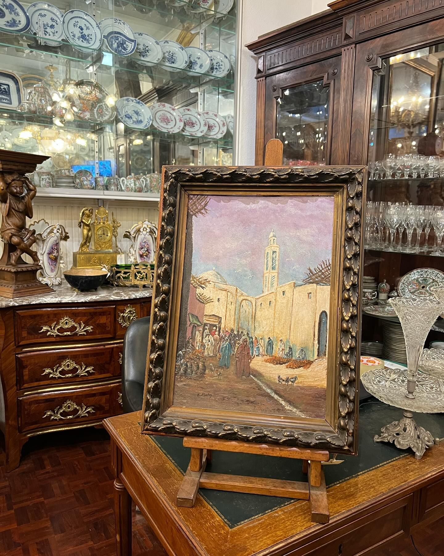 Pintura a óleo representando uma cena de rua em uma cidade do Oriente Médio, exposta em um cavalete.