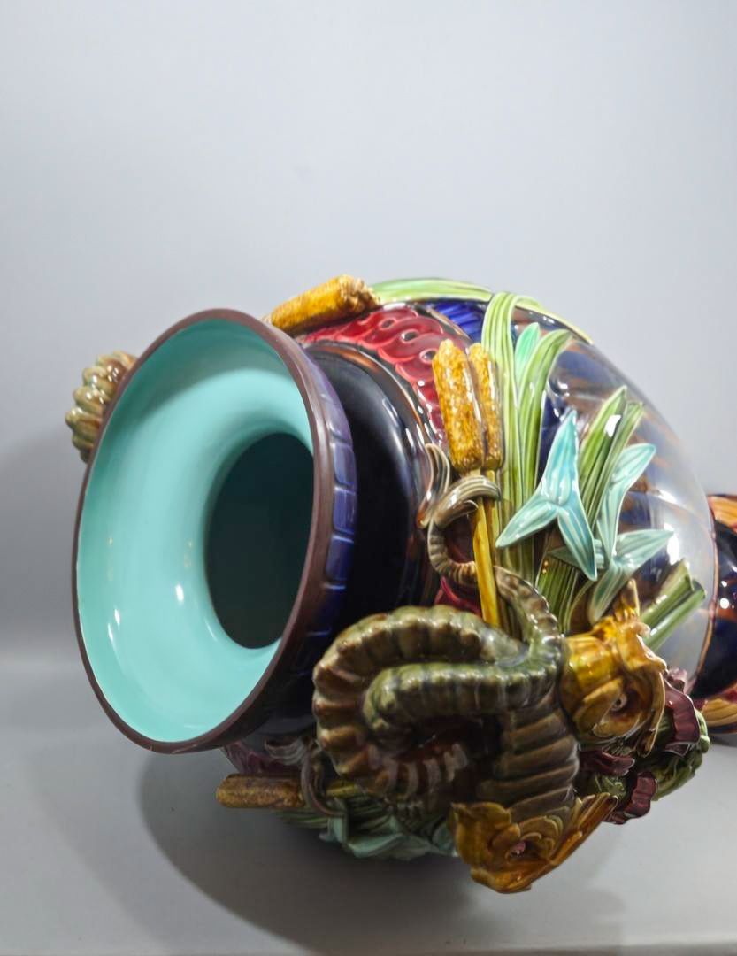 Vaso escultural de cerâmica com motivos aquáticos em tons de turquesa, amarelo e azul.