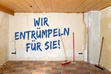 Ein Zimmer mit einem Besen und einem Schild an der Wand, auf dem steht: „Wir entrümpeln für sie“.