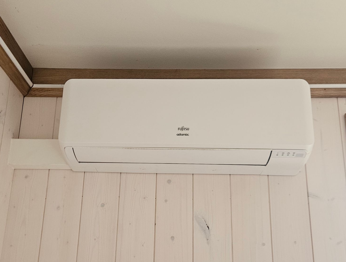 Unité de pompe à chaleur air-air à côté d'une maison blanche avec une pelouse verte.