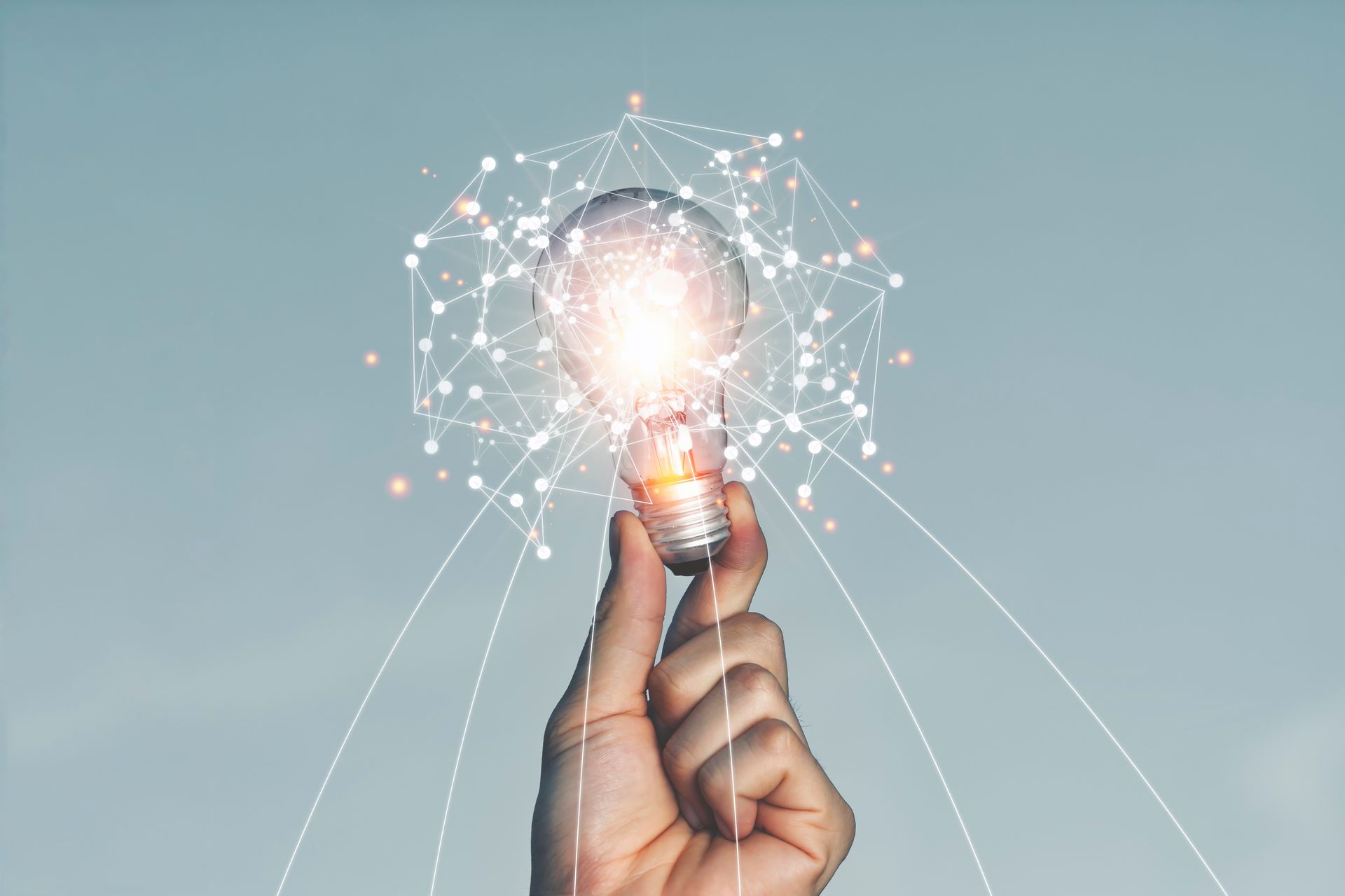 Une main tenant une ampoule allumée, entourée de points reliés entre eux, représentant l'innovation et les idées.