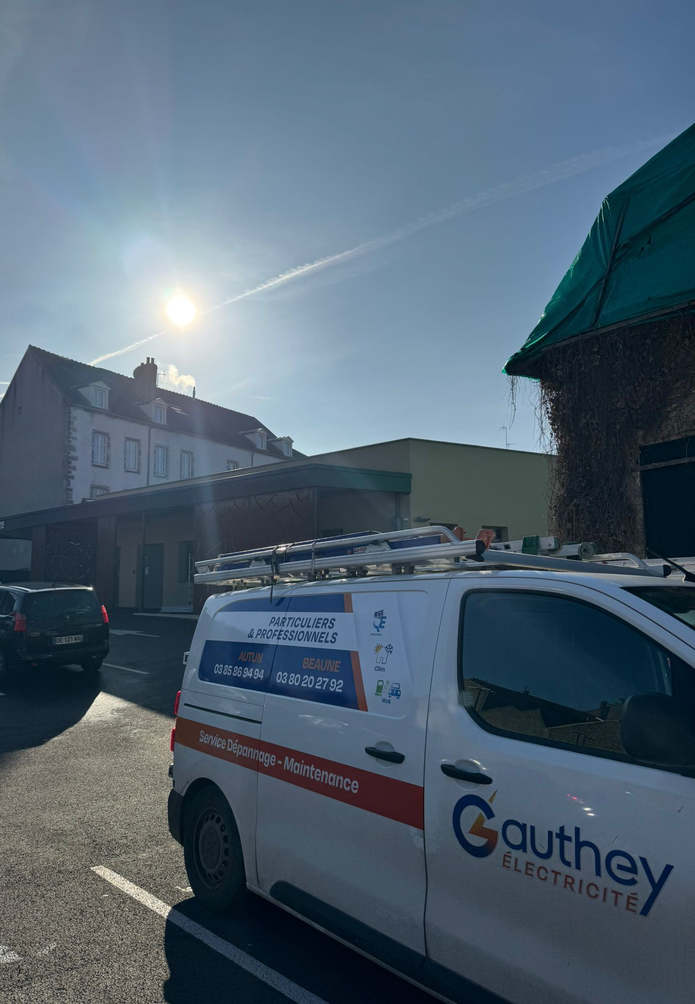 Une personne, les mains gantées, installe une ampoule. Des fils pendent du luminaire au plafond.