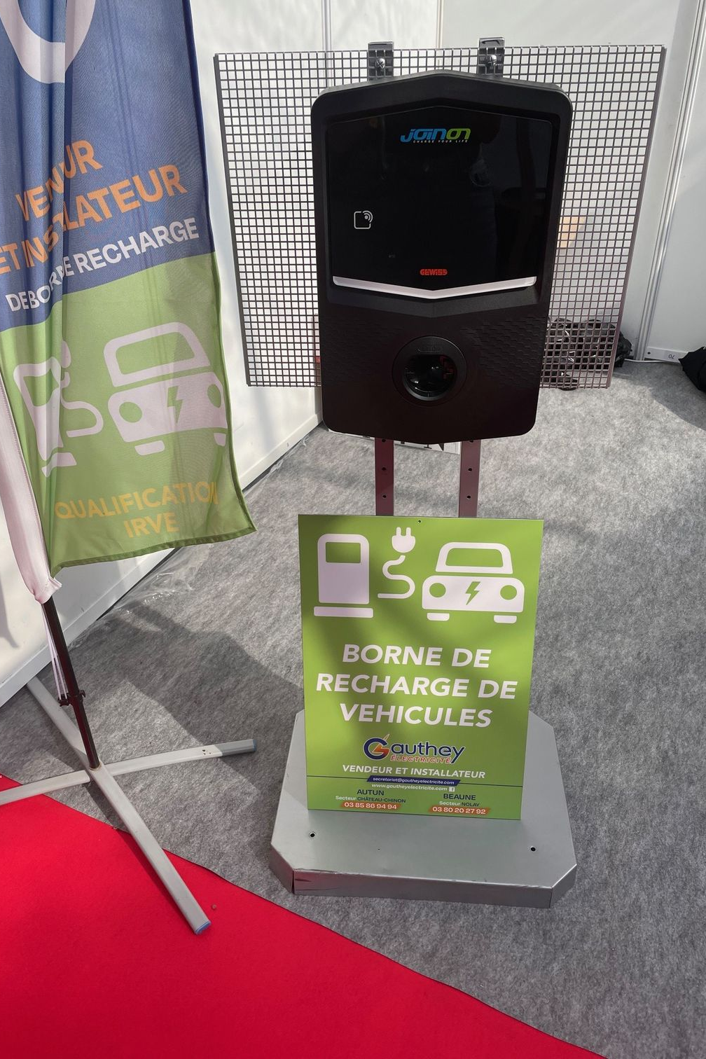 Voiture électrique blanche branchée, en charge devant une maison moderne.