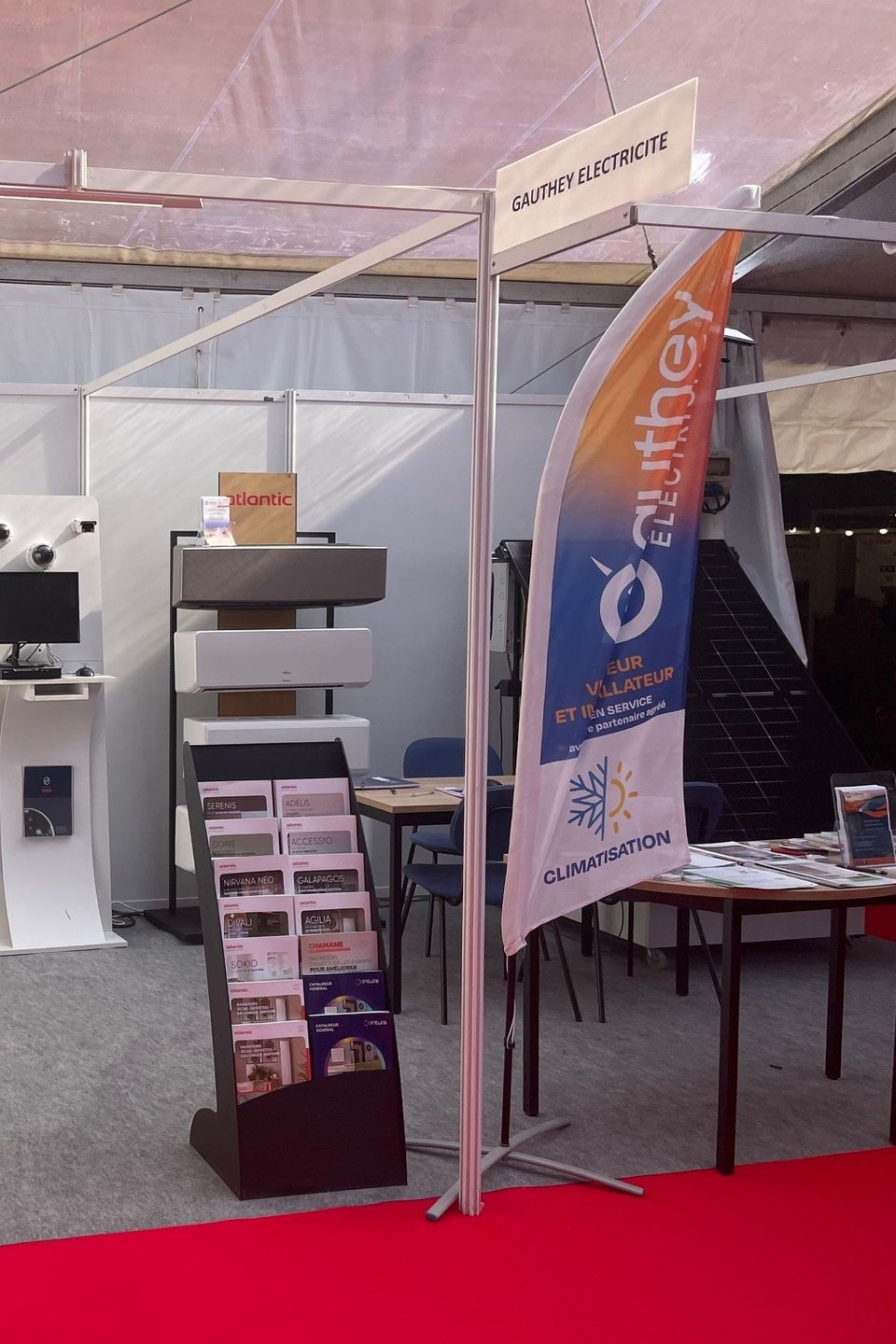 Un stand d'exposition avec un drapeau arborant le logo de l'entreprise et des brochures exposées.