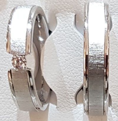 ein Paar Eheringe , die nebeneinander auf einer weißen Oberfläche sitzen .