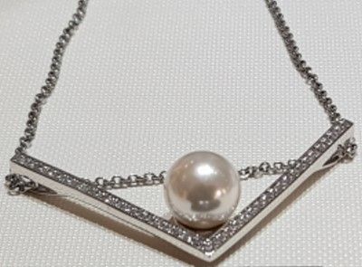 eine Nahaufnahme einer Halskette mit einer Perle und Diamanten