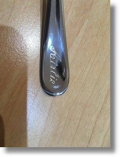 eine Nahaufnahme eines Löffels mit gravierten Namen auf einem Holztisch .