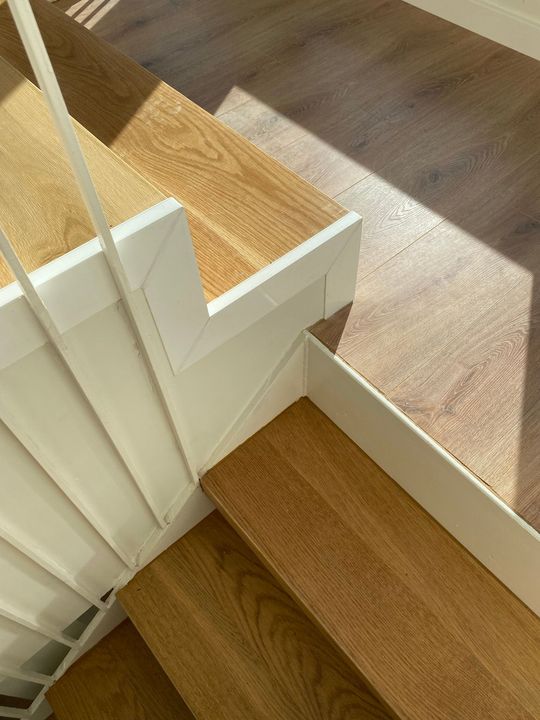 Primer pla d'una escala de fusta amb una barana blanca