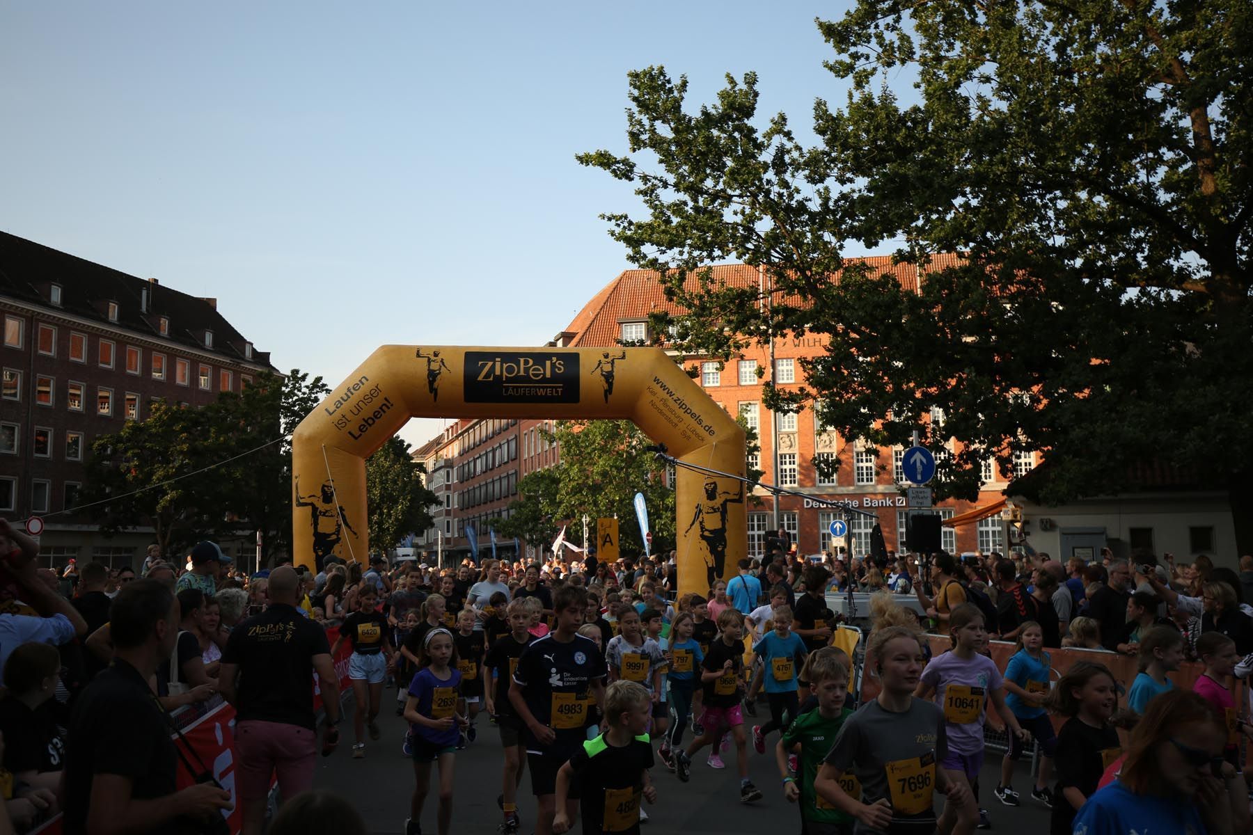 Bei Einbruch der Dunkelheit versammelte sich eine Menschenmenge am Start eines Straßenrennens unter einem gelben aufblasbaren Bogen.