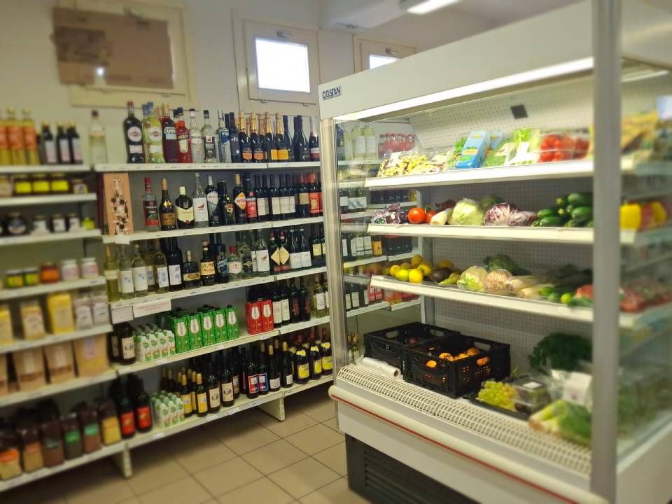 Interno di un supermercato con scaffali pieni di vino e prodotti refrigerati.