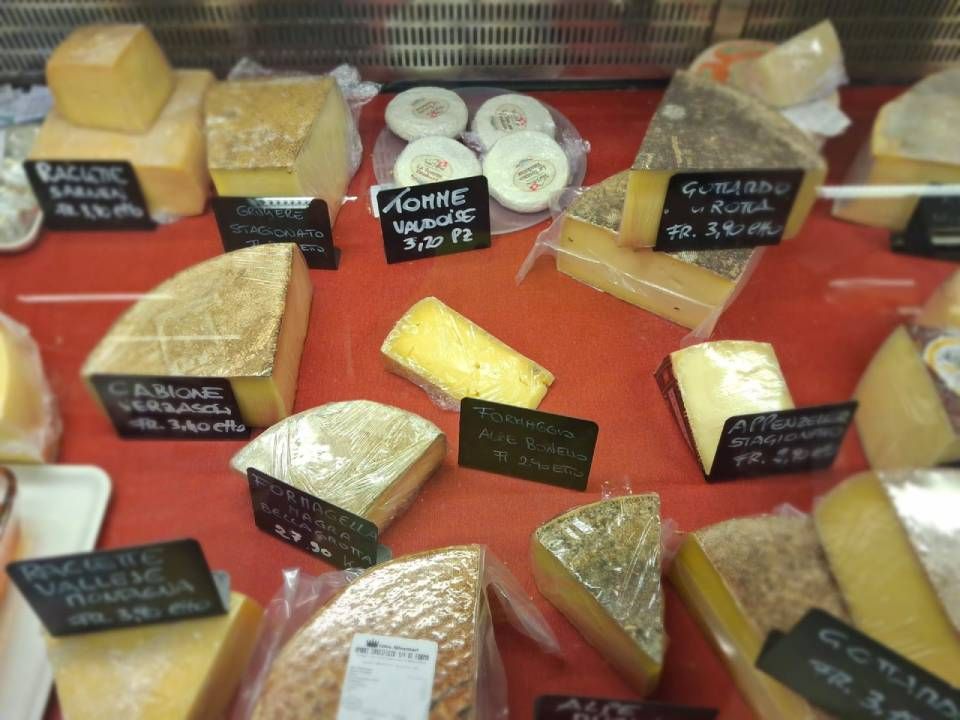 Vetrina espositiva per formaggi con vari tipi di formaggio a spicchi e a fette, etichettati con i prezzi.