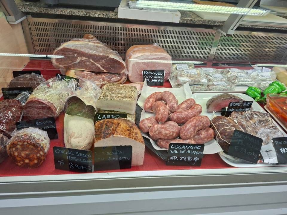 Vetrina piena di salumi vari: salame, salsicce, prosciutto e pancetta.