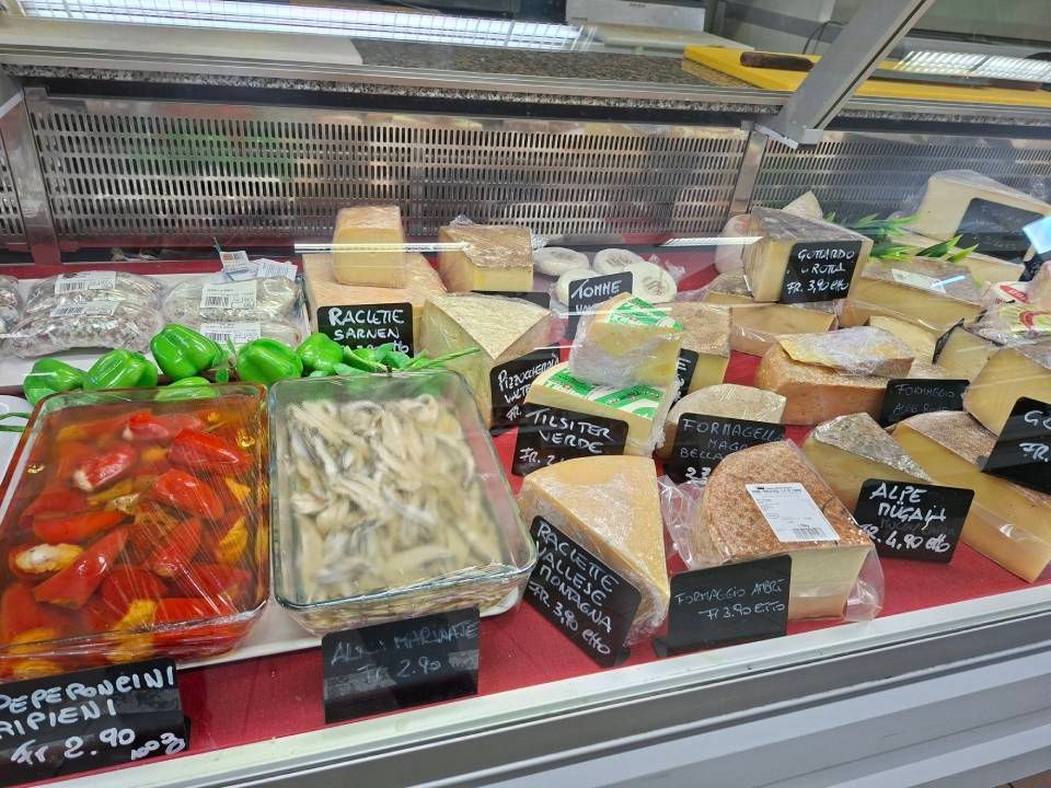 Vetrina con vari formaggi e verdure sottaceto.