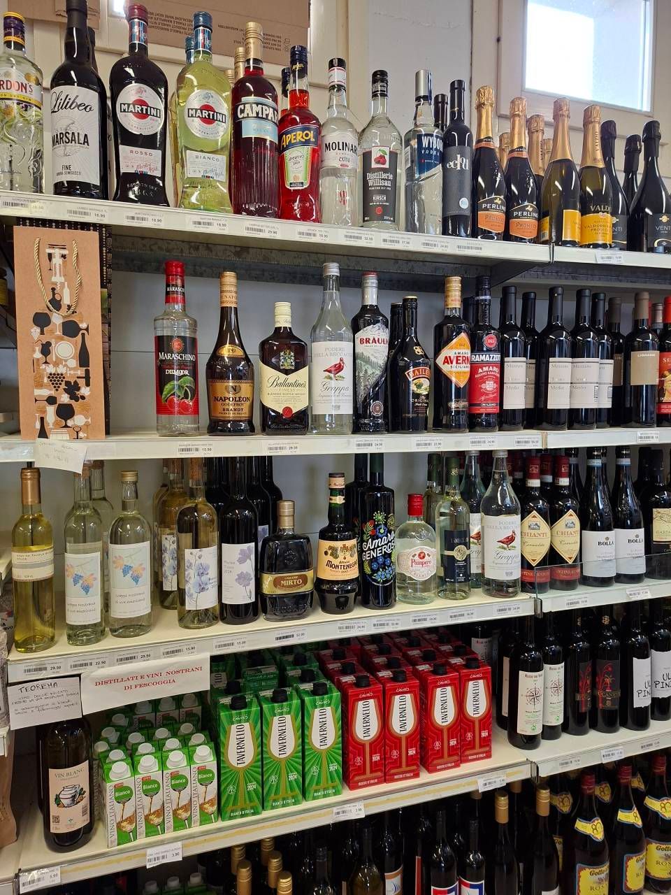 Scaffali pieni di bottiglie di alcolici in un negozio.