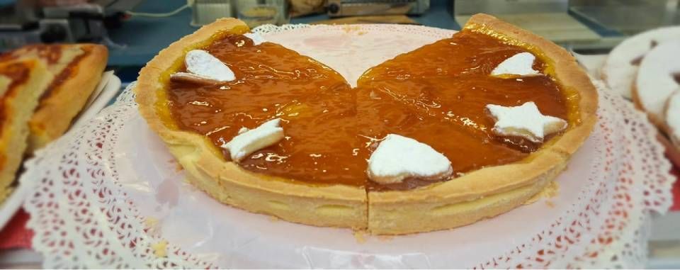 Una torta con ripieno all'arancia e forme di stelle/cuori bianchi, su un centrino di carta decorativo.
