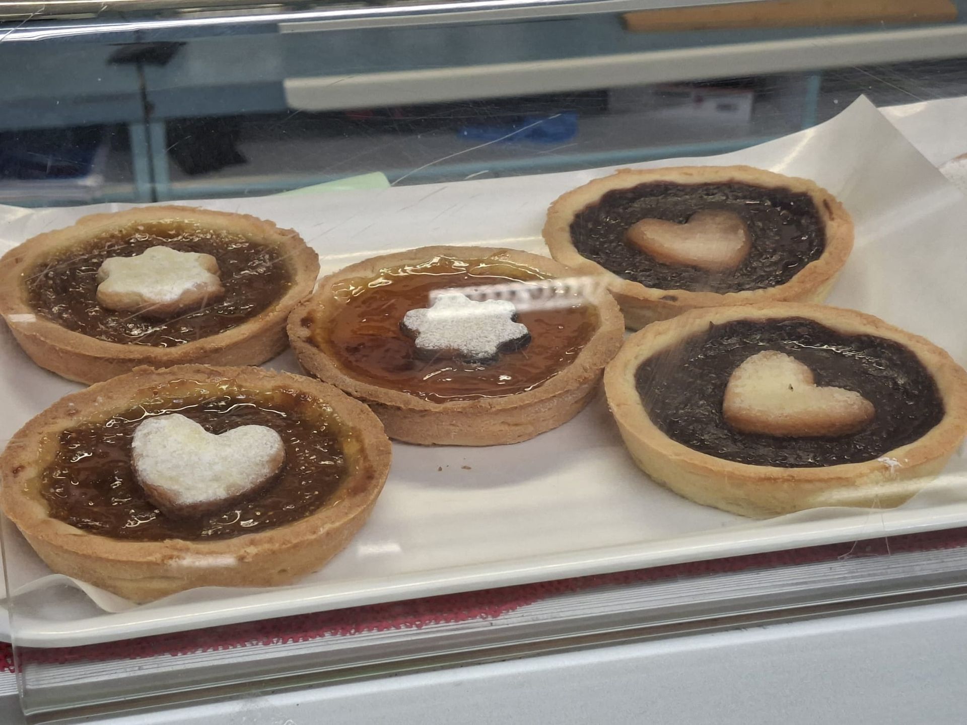 Vari tipi di pane e panini, alcuni spolverati di farina, su uno scaffale.