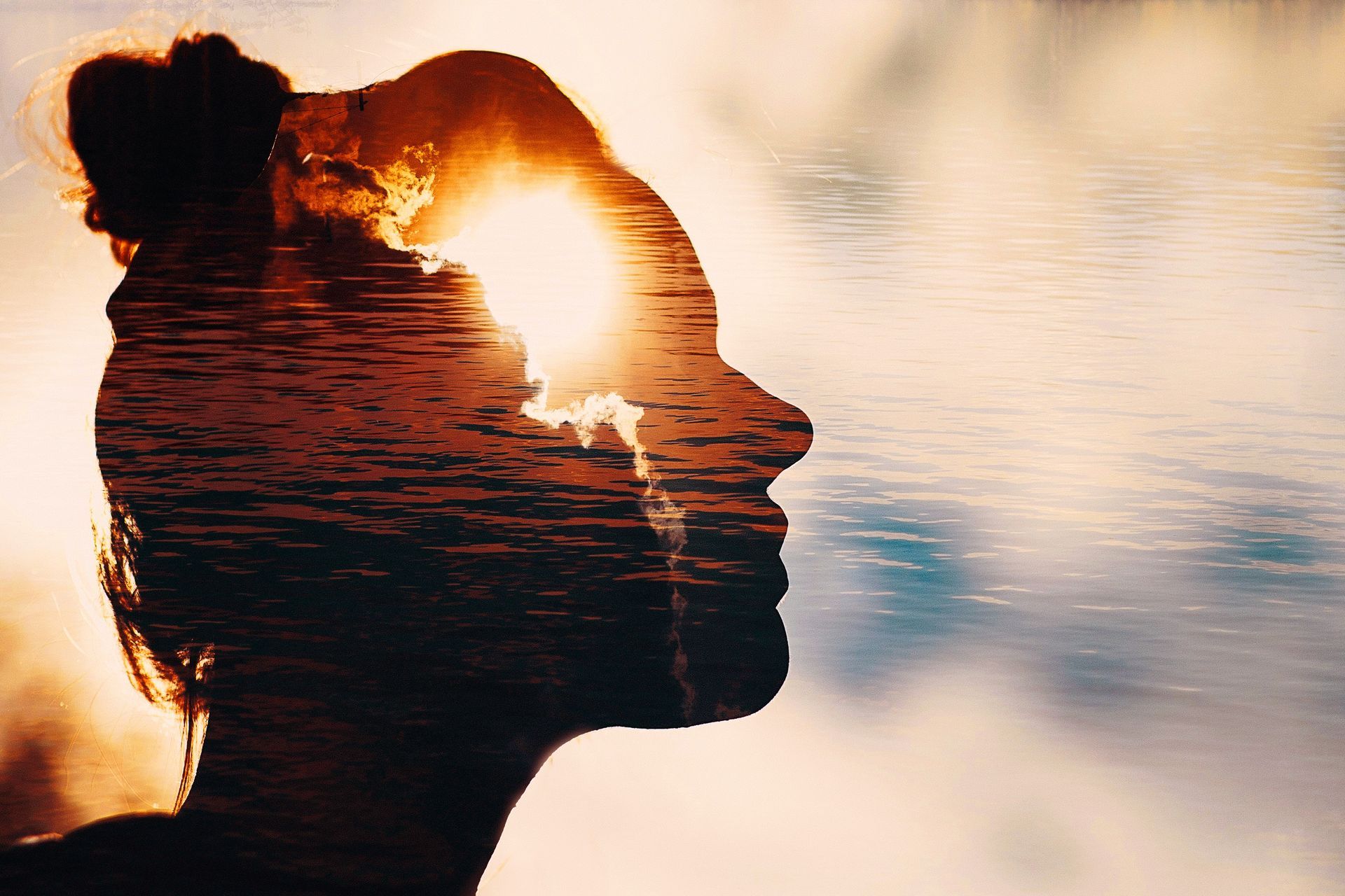 Silhouette d'une femme au coucher du soleil, son profil se fondant dans les vagues de l'océan et la lumière chaude.