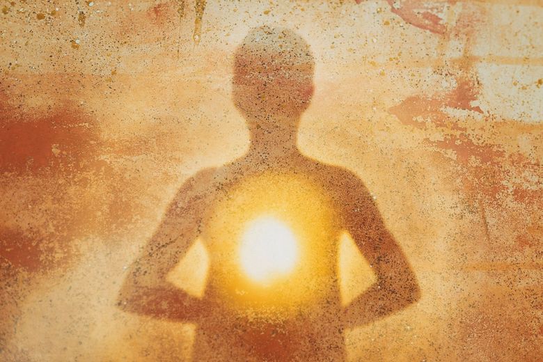 Silhouette d'une personne en méditation, une lumière éclatante au niveau de la poitrine se détachant sur un fond texturé aux tons chauds.