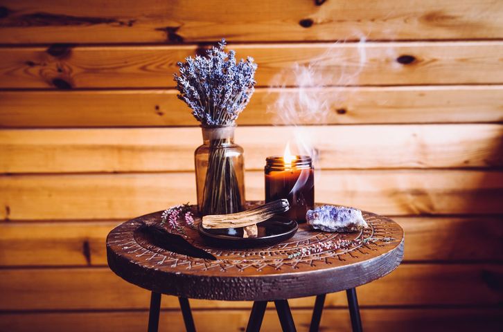Table en bois avec de la lavande séchée, des bougies et un livre dans un intérieur rustique et chaleureux